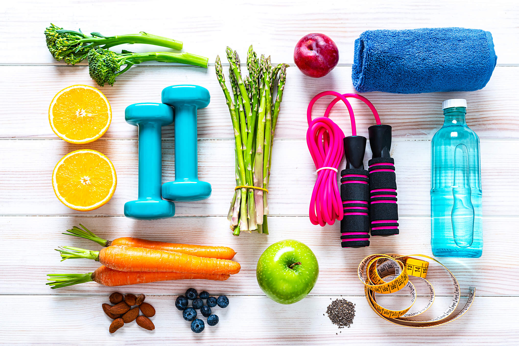 Healthy lifestyle items including fruits, vegetables, exercise equipment, and water bottle arranged on a table