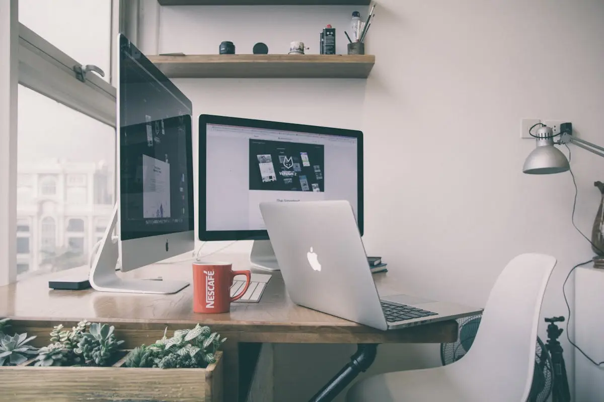 Remote work desk setup inside a furnished apartment with laptop and desktop computer