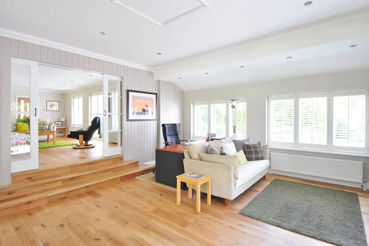 Spacious furnished living room with home office area and natural lighting