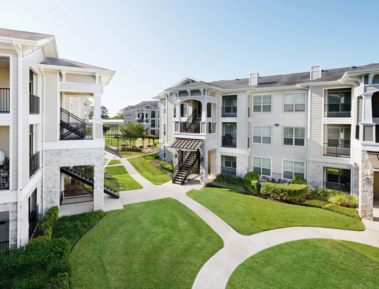 Exterior view of a modern apartment community with landscaped walkways and green space