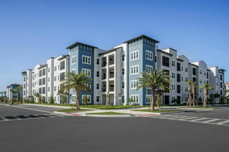 Exterior view of Sorrento Apartments in Sarasota featuring modern architecture, palm trees, and upscale apartment buildings