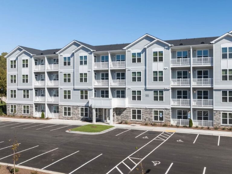 Exterior view of Alexander Crossing apartment community featuring a modern four story residential building with private balconies, ample parking, landscaped grounds, and contemporary architectural design.