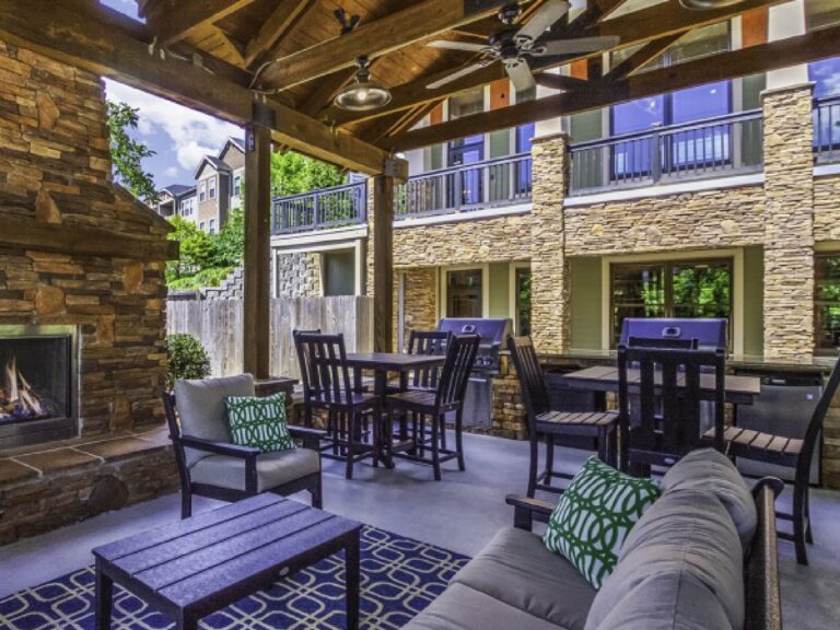 Covered outdoor pavilion featuring grilling stations, fireplace, lounge seating, dining tables, and rustic mountain-inspired architecture.