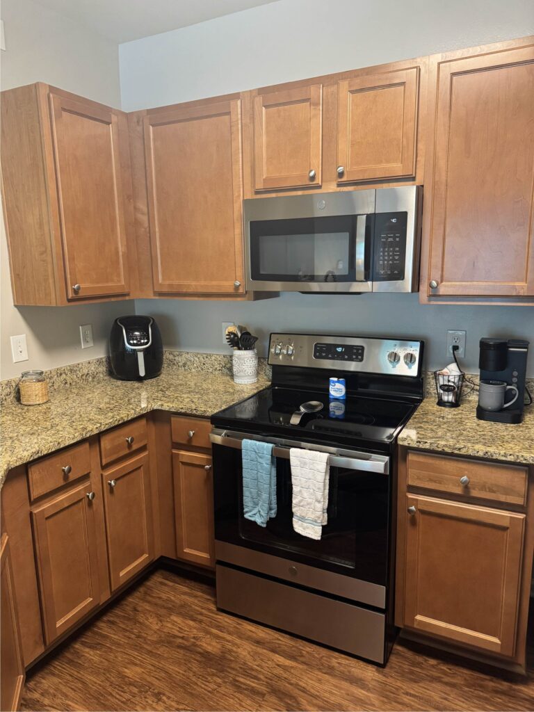 Fully equipped kitchen featuring stainless steel appliances, granite countertops, wood cabinetry, and small appliances including a coffee maker and air fryer.