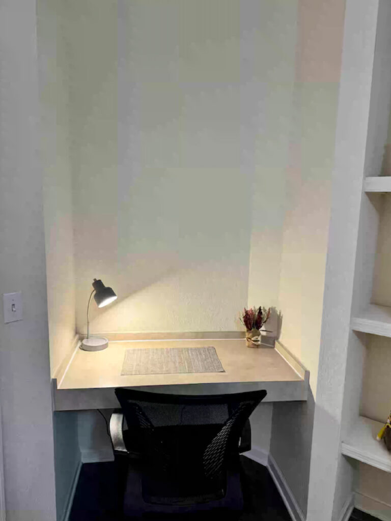 Dedicated workspace nook at Ballantrae Apartments with built in desk, office chair, task lighting, and shelving