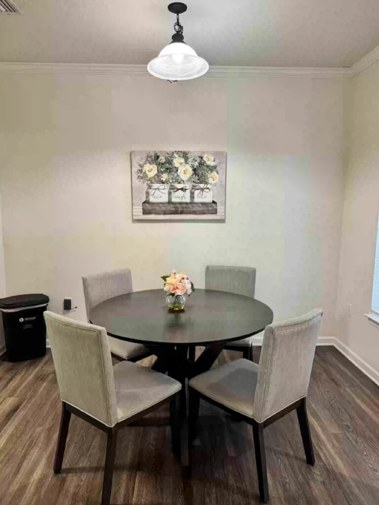 Dining area at Ballantrae Apartments with round dining table, four upholstered chairs, pendant lighting, and furnished apartment setup