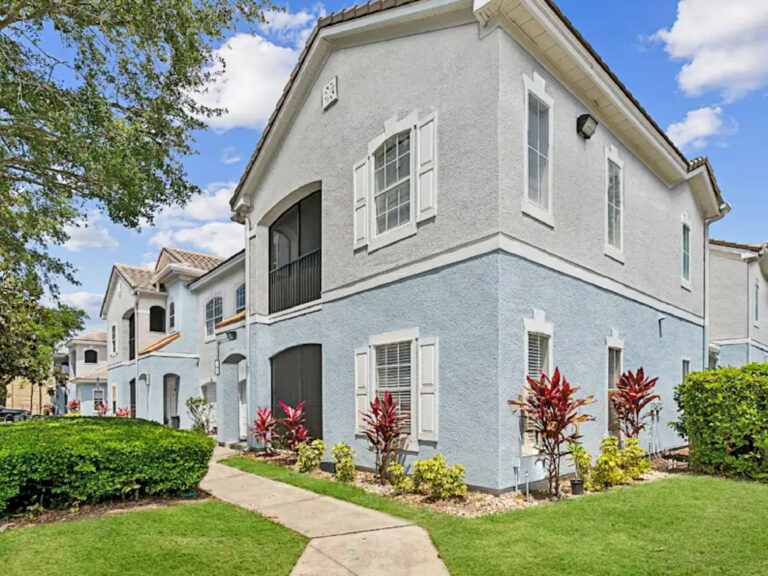 Exterior view of Ballantrae Apartments in Sanford with landscaped walkways, tropical plants, and multi building residential community