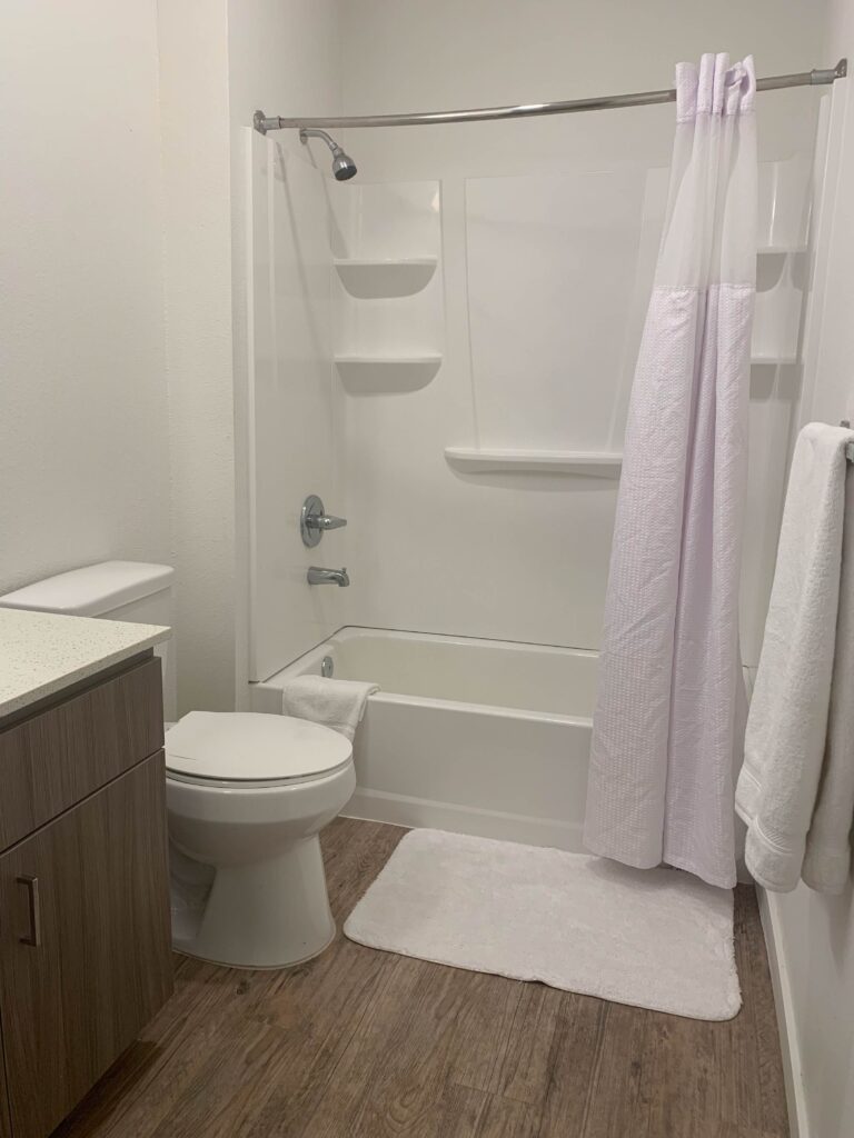 In-unit laundry area at Cielo Luxury Living featuring a full-size Whirlpool front-loading washer and dryer with decorative storage baskets and modern wall art.
