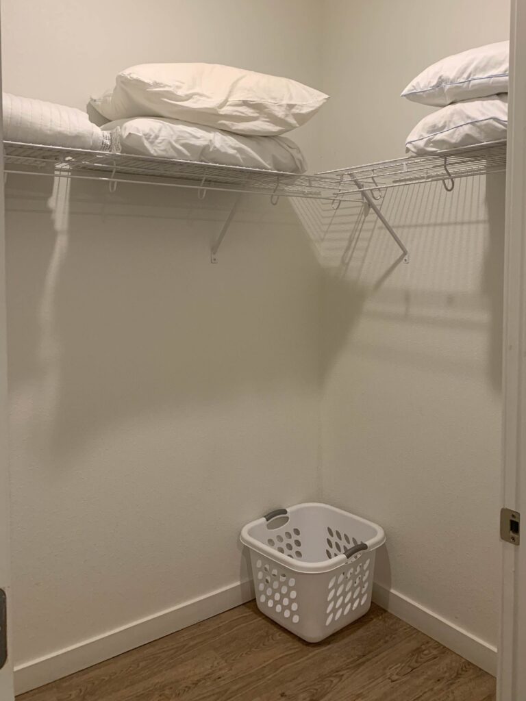 Walk-in closet at Cielo Luxury Living featuring wire shelving, extra pillows, a laundry basket, and ample storage space for clothing and personal belongings.
