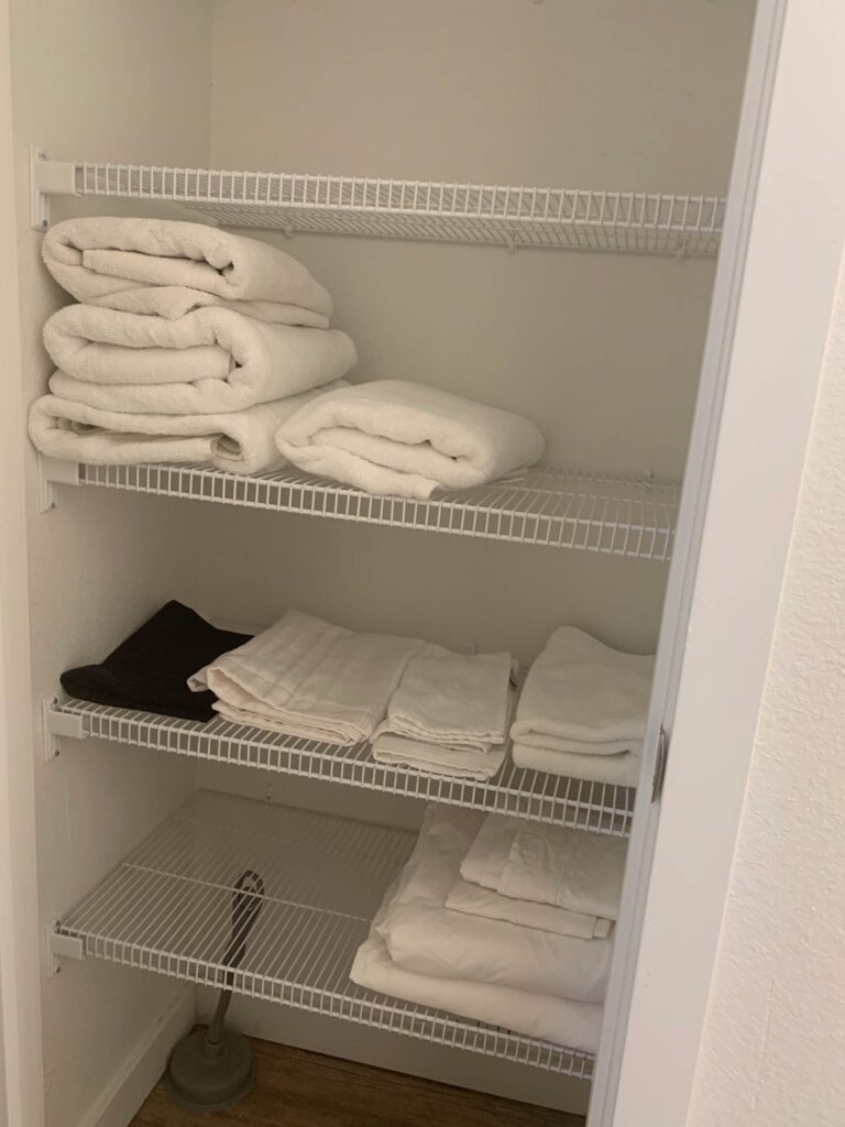 Linen closet at Cielo Luxury Living stocked with fresh towels, linens, extra bedding, and household essentials neatly organized on multiple storage shelves.