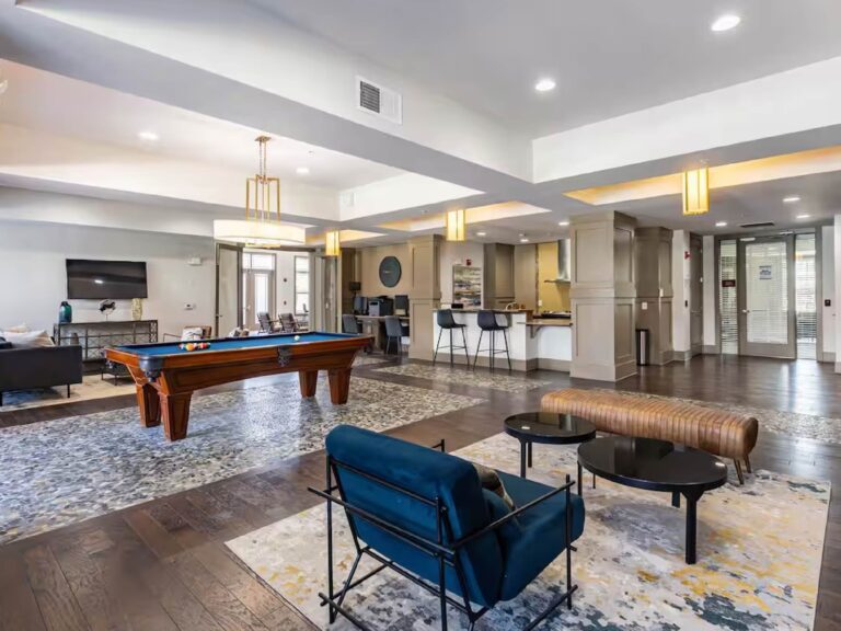 Modern resident clubhouse at Creekstone at RTP featuring lounge seating, a pool table, business center workstations, entertainment areas, and gathering spaces for residents and guests.