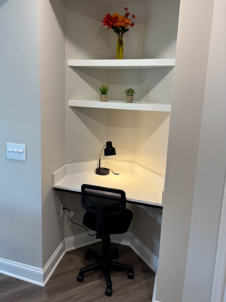 Built in workspace at Creekstone at RTP featuring a dedicated desk area with task lighting, shelving, office chair, and a quiet nook suitable for remote work or studying.