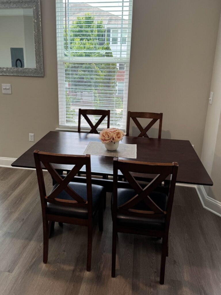 Dining area at Creekstone at RTP featuring a four person dining table, matching chairs, decorative centerpiece, large window, and an open layout suitable for meals, work, or entertaining.