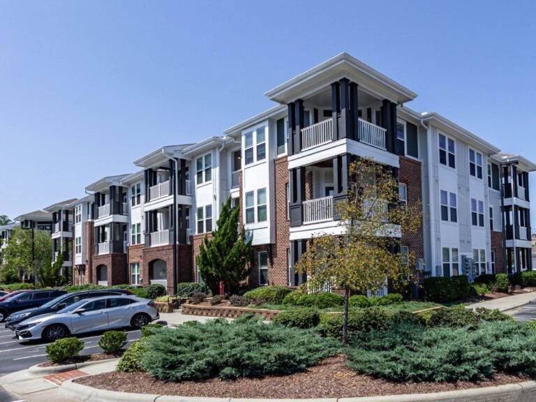 Exterior view of Creekstone at RTP featuring modern apartment buildings with brick and white siding accents, private balconies, landscaped grounds, and convenient on site parking.