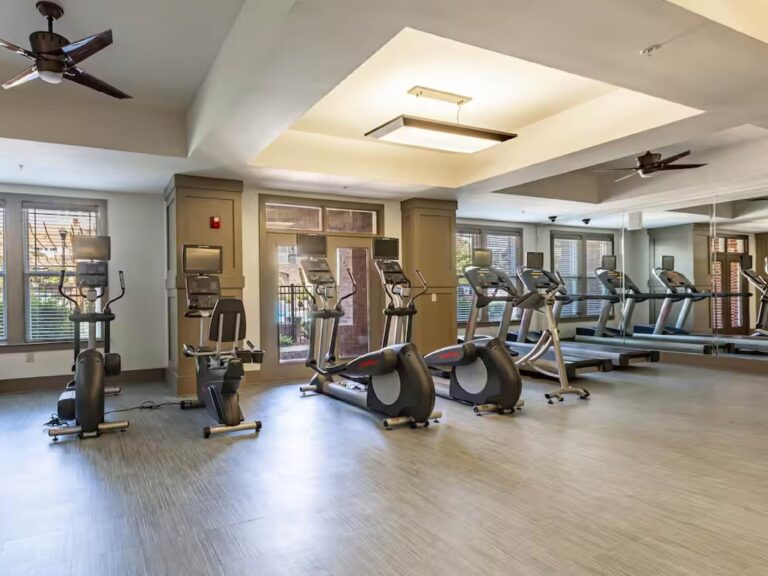 Community fitness center at Creekstone at RTP featuring cardio equipment, treadmills, ellipticals, stationary bikes, strength machines, mirrored walls, and spacious workout areas.