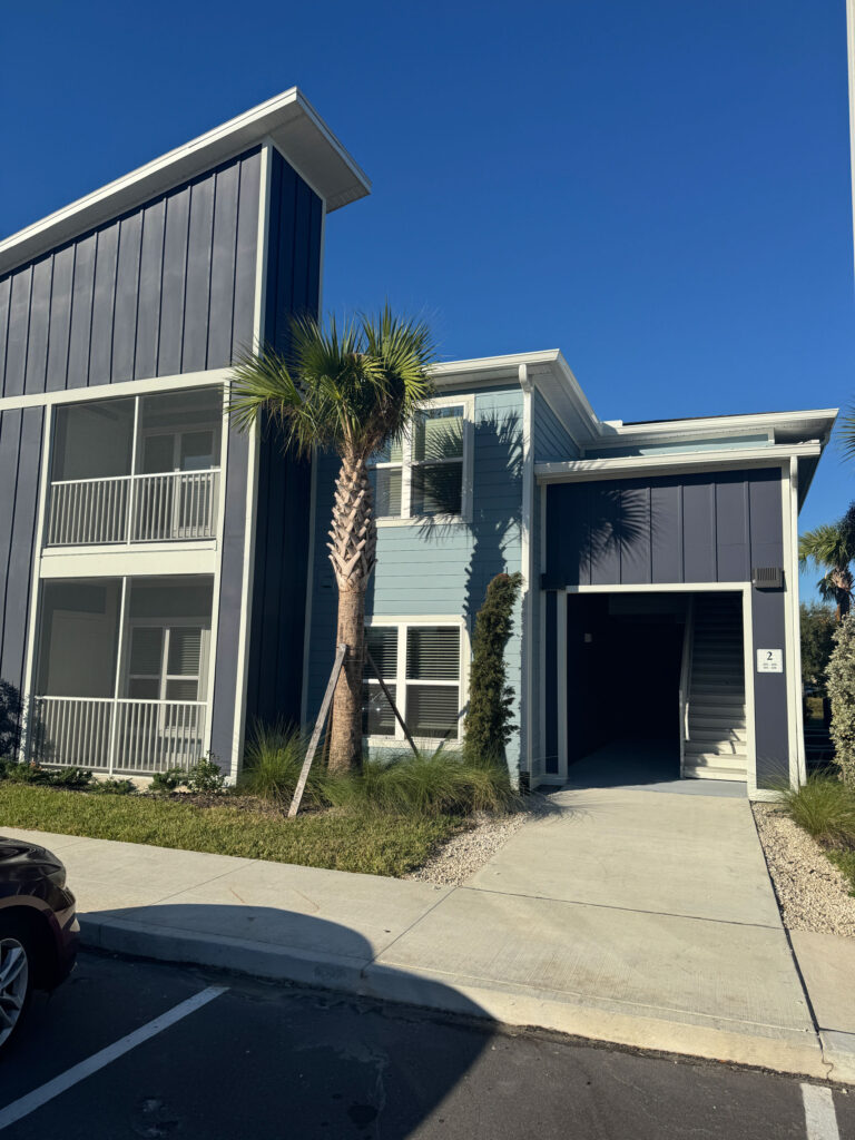 Exterior view of Dream Winter Haven apartment community featuring modern architecture, palm trees, and private screened balconies in Winter Haven Florida