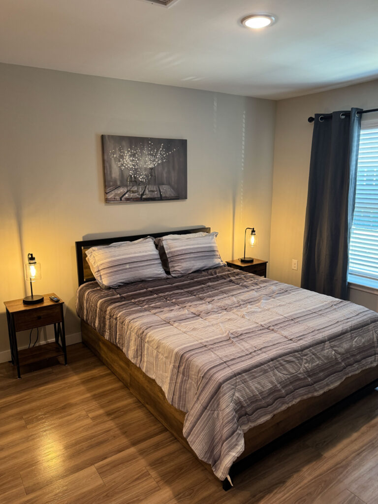 Modern furnished bedroom at Dream Winter Haven featuring a queen size bed, wood style flooring, and contemporary lighting