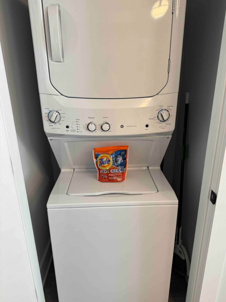 In-unit stacked washer and dryer tucked into a dedicated laundry closet, complete with detergent provided for guest convenience.