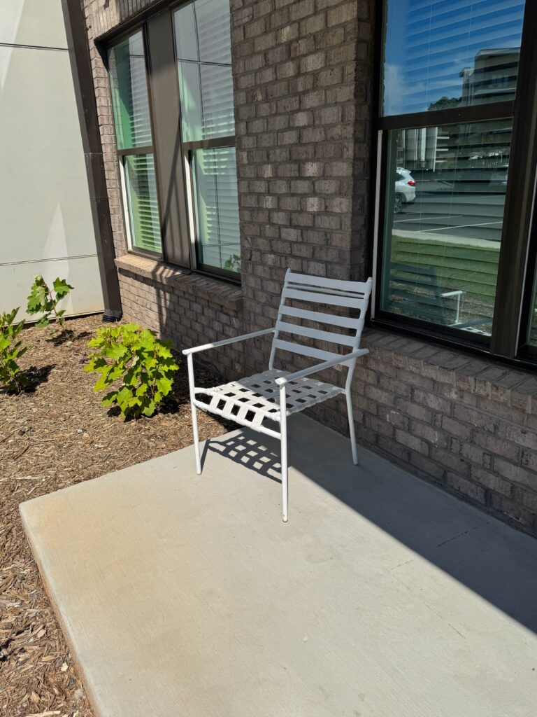 Private ground-level patio featuring outdoor seating, landscaped surroundings, and direct access from the apartment residence.