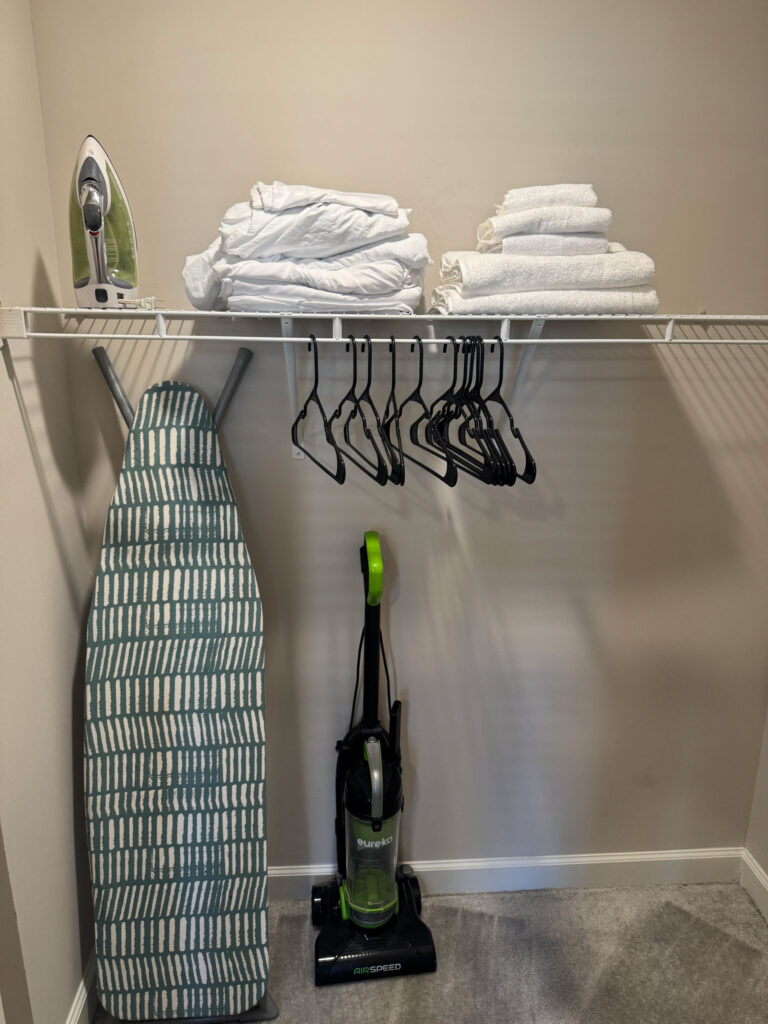 Walk in closet at Evergreen at Southwood featuring linens, hangers, ironing board, vacuum, and guest storage space in Tallahassee Florida