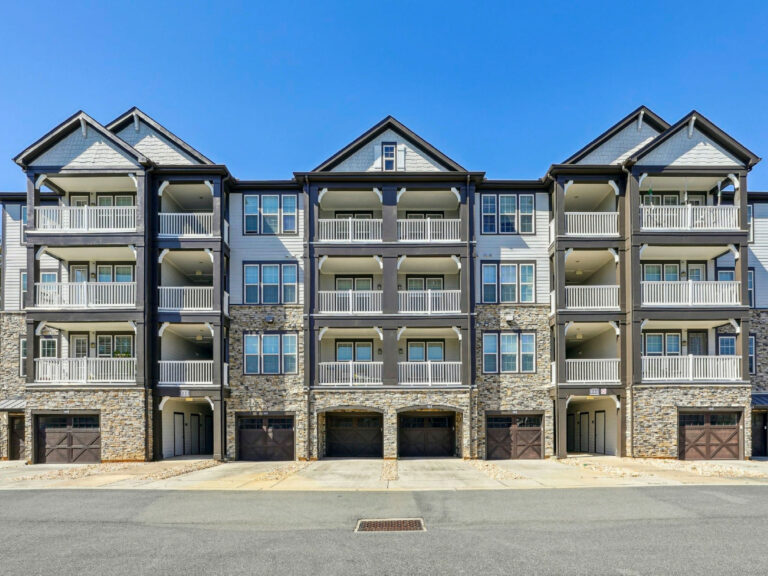 Exterior view of Evergreen at Southwood apartment community featuring multi level residences, private balconies, and attached garages in Tallahassee Florida