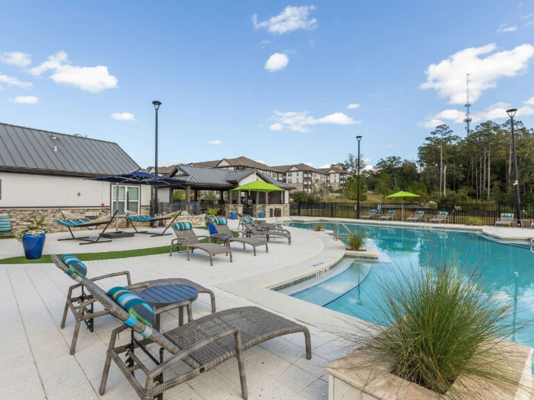 Resort style swimming pool at Evergreen at Southwood in Tallahassee featuring lounge seating, shaded relaxation areas, and upscale apartment amenities