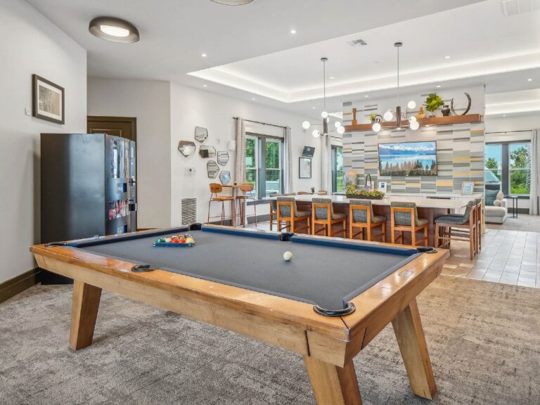 Modern resident lounge with a billiards table, bar seating, pendant lighting, and contemporary gathering spaces.