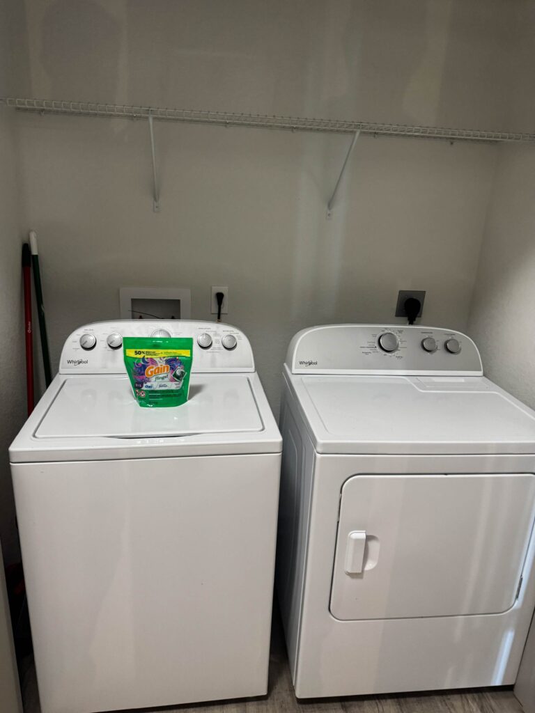 In-unit laundry area with full-size Whirlpool washer and dryer for guest convenience.