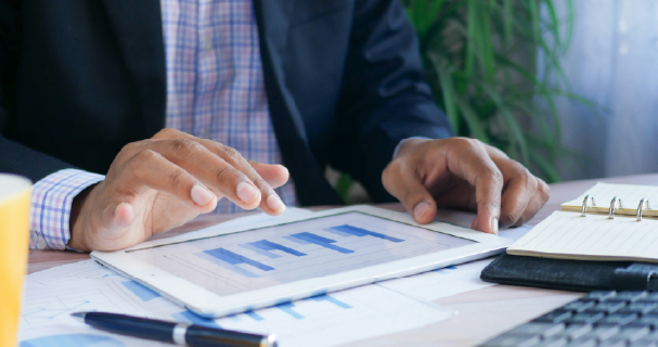 Business professional reviewing financial information on a tablet, representing insurance claims management, temporary housing coordination, and policyholder support services.