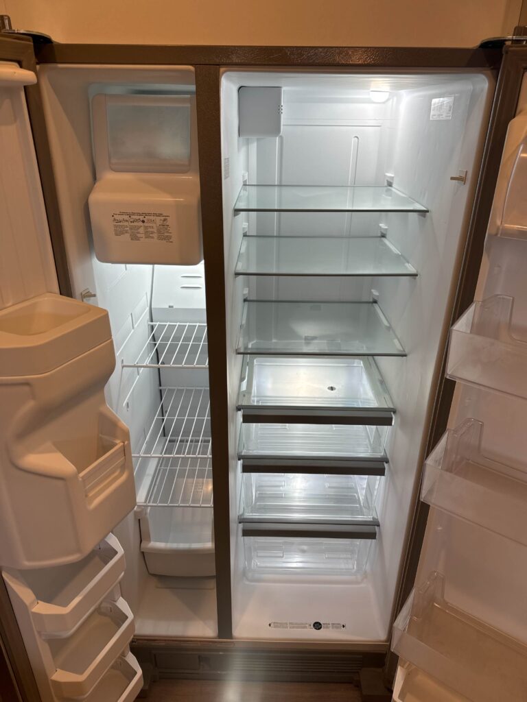 Full size refrigerator and freezer inside a furnished apartment at Lenox Grand Apartments in Austin, Texas featuring adjustable glass shelving, spacious storage compartments, and built in ice maker.