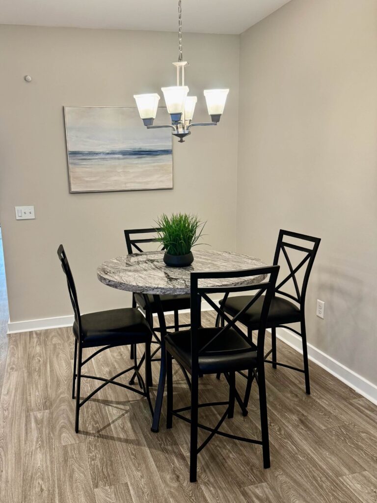 Modern dining area featuring a round dining table with seating for four, contemporary lighting, and stylish décor adjacent to the kitchen and living spaces.