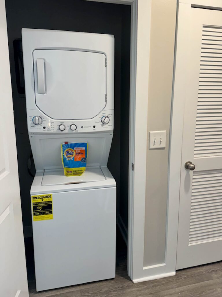 Convenient in-unit stacked washer and dryer located within a dedicated laundry closet, complete with laundry supplies for guest use.