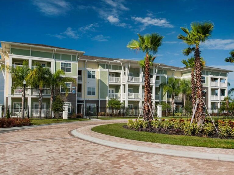 Exterior view of M North Orlando apartment community with palm trees, landscaped grounds, and multi story residential buildings.