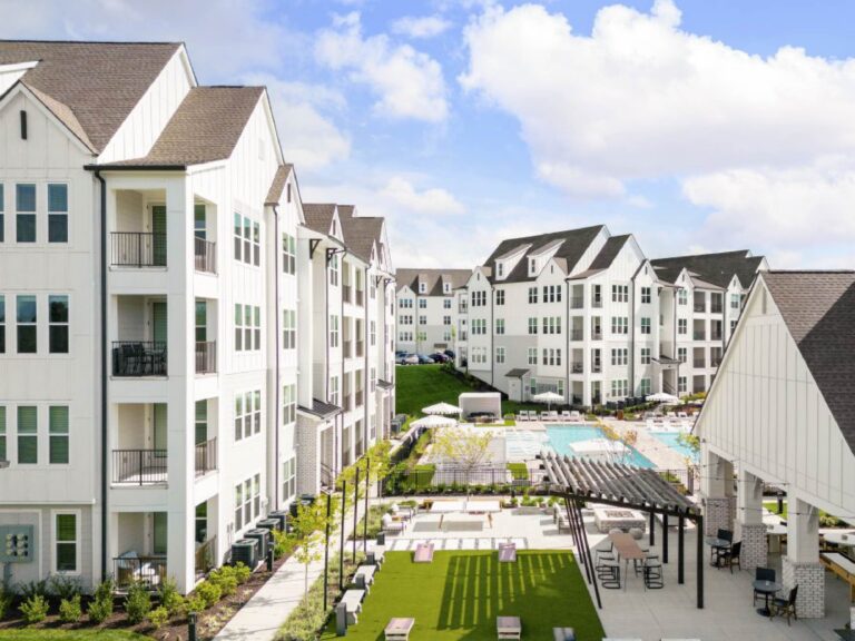 Aerial view of Maxwell Apartments in Nashville featuring modern white residential buildings, a resort style swimming pool, outdoor lounge areas, covered gathering spaces, landscaped courtyards, and recreational amenities.