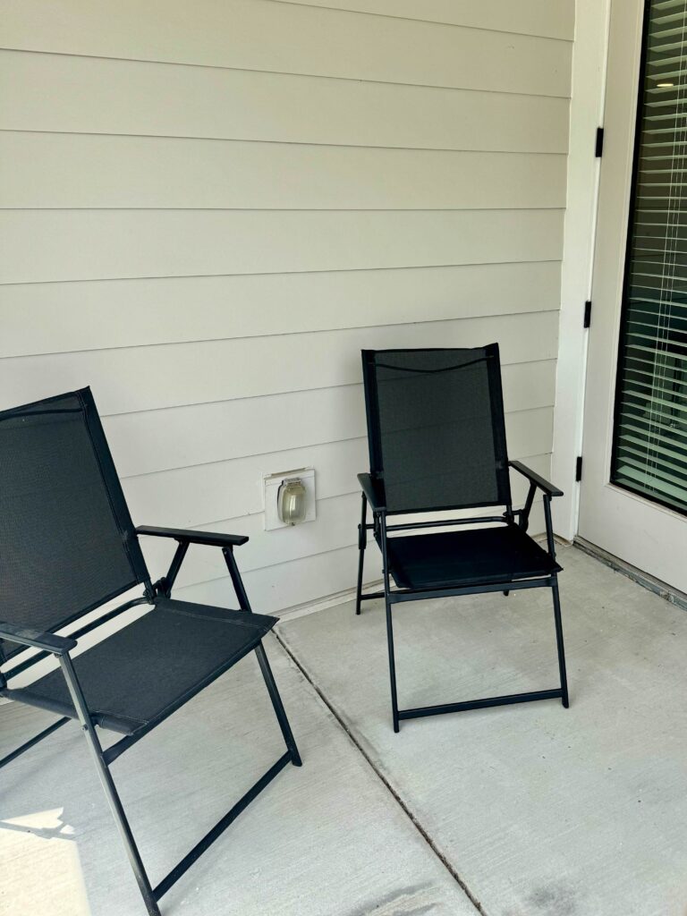 Private outdoor patio at Maxwell Apartments featuring two patio chairs and direct access from the apartment living space.