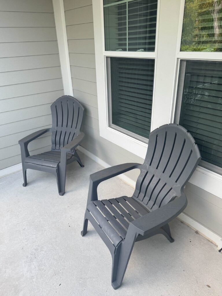 Private outdoor patio with two gray Adirondack-style chairs beside large windows.