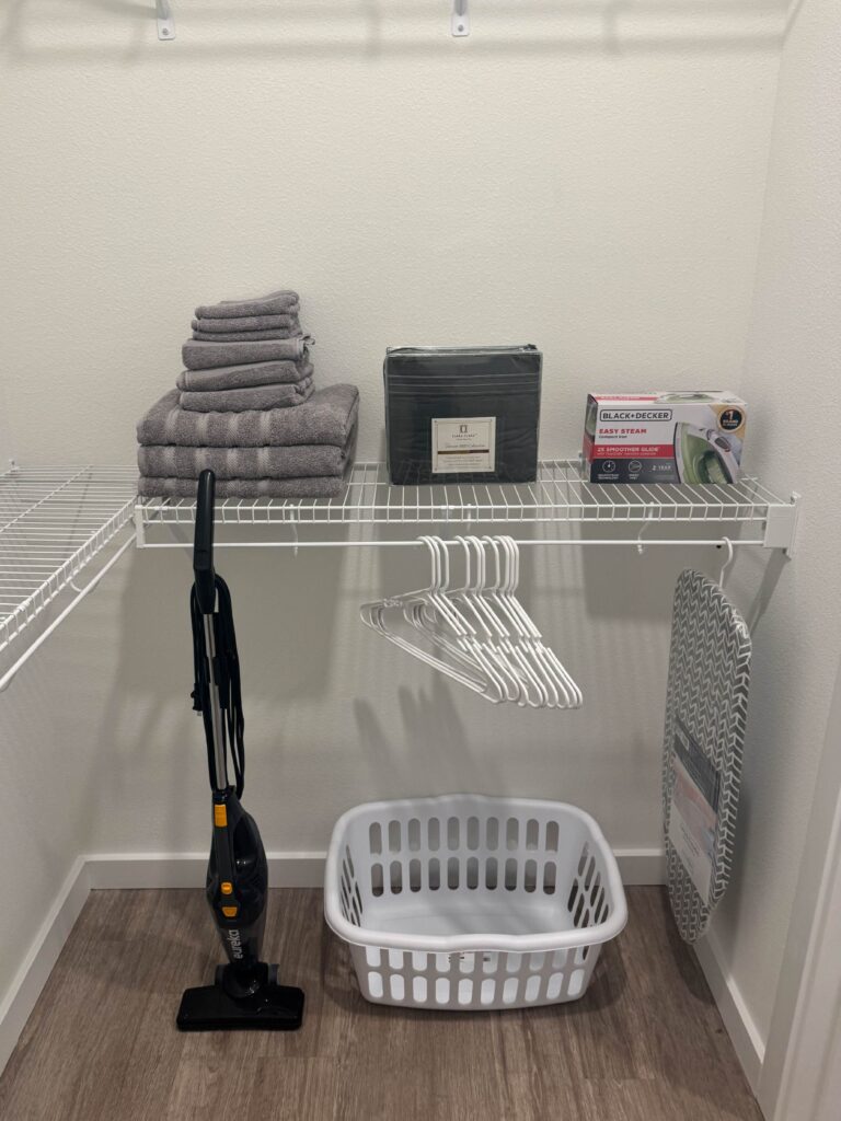 Spacious walk-in closet with shelving, hanging space, linens, ironing board, and guest convenience essentials.