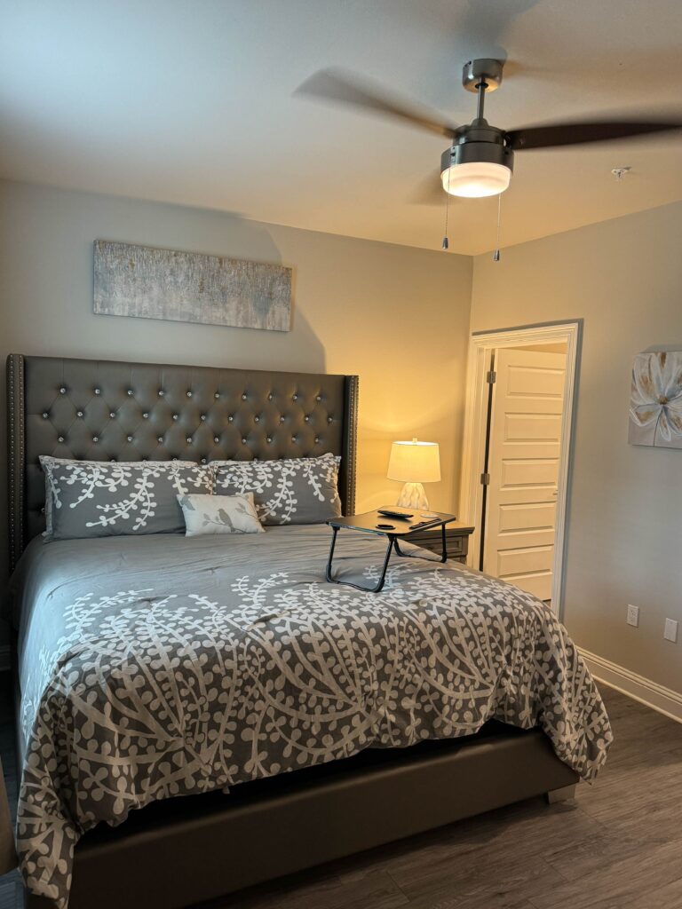 Elegant primary bedroom featuring a king bed, tufted upholstered headboard, ceiling fan, bedside lighting, and contemporary décor.