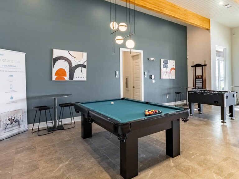 Resident clubhouse game room at Oasis at Southpark featuring a pool table, foosball table, modern lighting, and contemporary lounge seating.