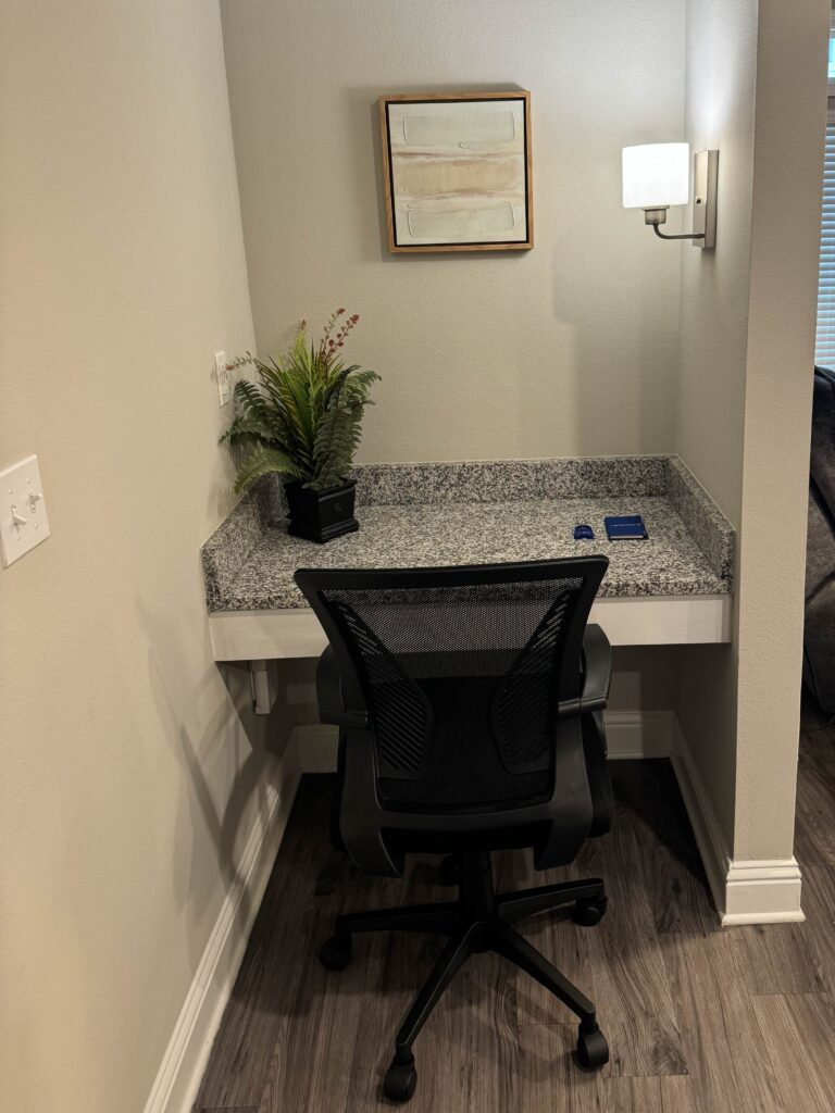 Compact built-in workspace featuring a granite desktop, ergonomic office chair, task lighting, and a quiet alcove design.