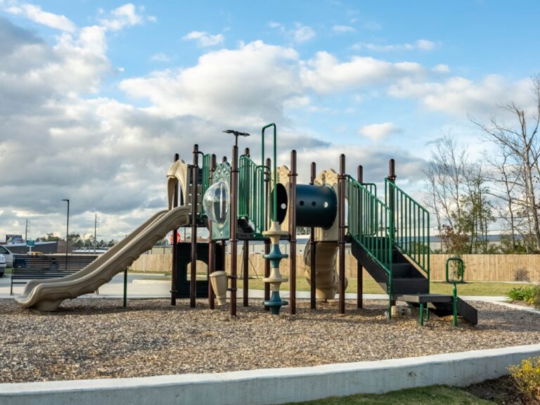 Community playground at Oasis at Southpark featuring slides, climbing structures, tunnels, and a dedicated outdoor recreation area for children.