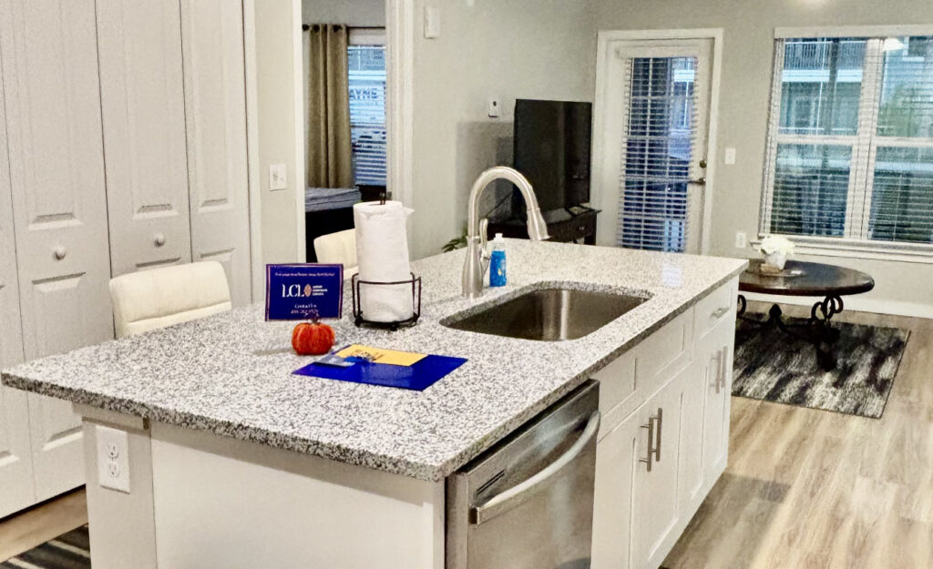 Interior of a furnished Luxury Corporate Lodging apartment with welcome packet, keys, and stocked kitchen essentials