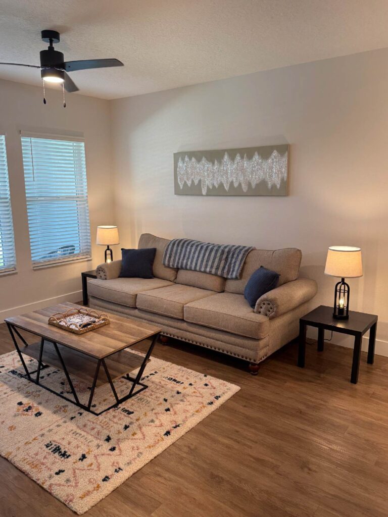 Modern furnished living room at Sorrento Apartments with sofa, accent lighting, coffee table, and contemporary décor