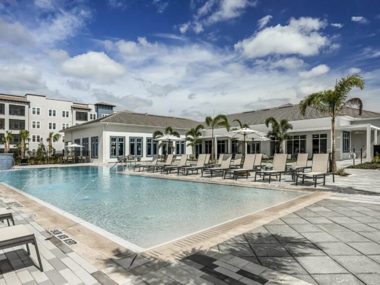 Resort style pool at Sorrento Apartments in Sarasota featuring luxury lounge seating, palm trees, and upscale community amenities