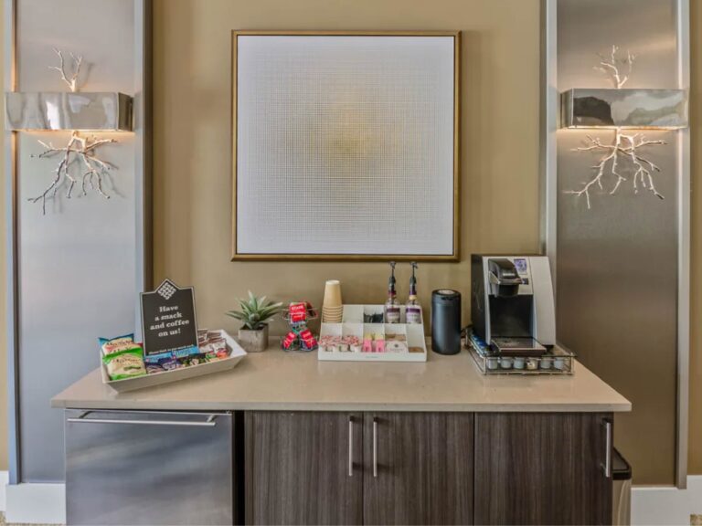 Community coffee bar at Tapestry Bocage featuring complimentary coffee service, refreshments, snack station, and modern cabinetry within the resident clubhouse.