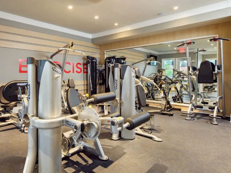 Modern fitness center at Tapestry Bocage featuring cardio equipment, strength training machines, free weights, and mirrored workout space.
