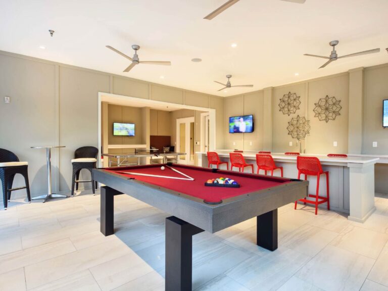 Resident clubhouse lounge at Tapestry Bocage featuring a billiards table, bar seating, televisions, gathering areas, and modern community amenities.