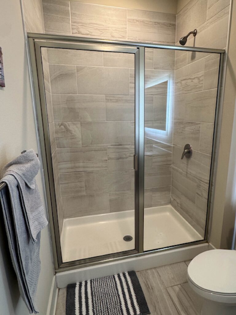 Modern bathroom with a glass walk-in shower, gray tile walls, and minimalist finishes.