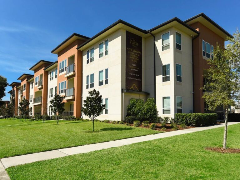 Exterior view of The Mayfair apartment community featuring modern architecture, landscaped grounds, and apartment balconies.