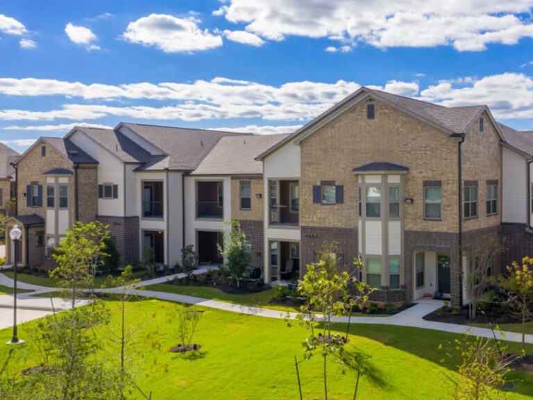 Modern luxury apartment buildings at Vale Apartments in the Spring/Houston area featuring landscaped courtyards, walking paths, contemporary architecture, and professionally maintained grounds.